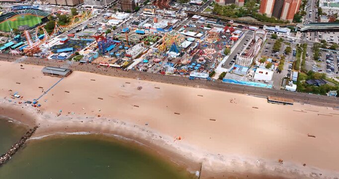 Distancing from almost empty sandy beach in Coney Island. Aerial view on the amusement park with numerous attractions. Brooklyn, NY, USA.