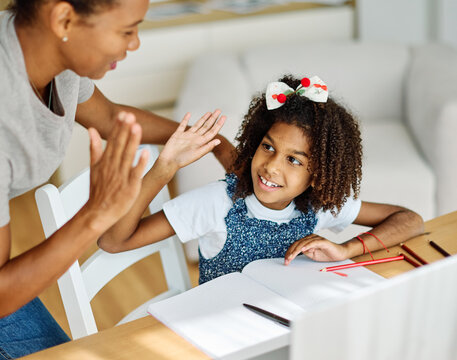 Mother and daughter doing homework with laptop at home. Mother and teenage daughter girl using laptop. Mother and daughter giving high five hand to each other. Teamwork and cooperation concept