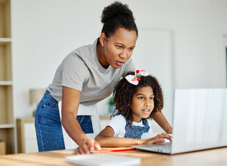 Mother and daughter doing homework with laptop at home. Mom, dad and teenage black girl happy using laptop. Teen girl and parents sitting at home working with notebook