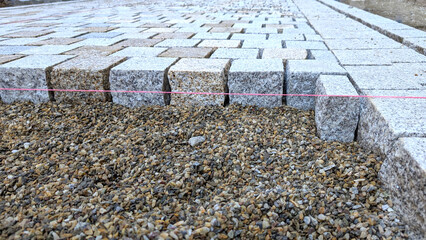 Paving stones laying procedure in a residential area. Stages of durable pathway tiling.