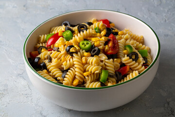 Fresh homemade colorful vegan fusilli pasta salad with olive, corn, tomato and jalapeno close-up in...