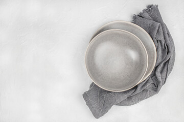 Empty gray ceramic plates with linen napkin on white textured background. top view. copy space