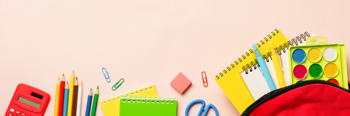 School backpack with stationery on colored background. Flat lay with copy space