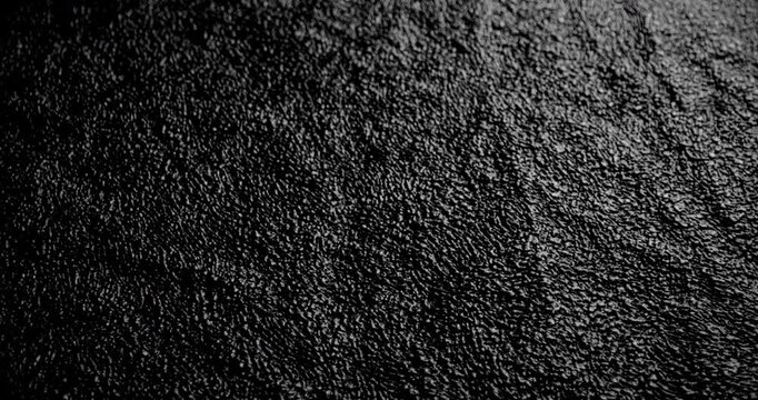 Granular Black Surface with Deep Creases. Video showing smooth movement across a dark textured surface with visible creases and grain, great for abstract visuals and background applications.