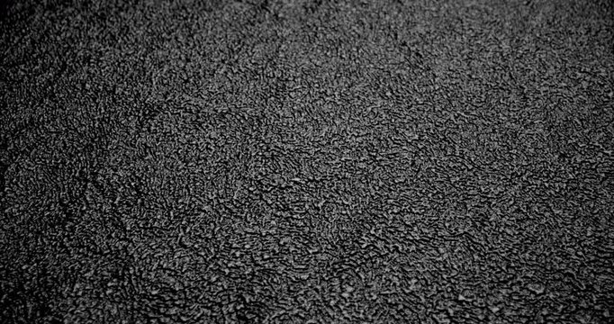 Black Rough Asphalt Texture in Motion. Video featuring smooth linear movement across a dark asphalt surface with detailed rough structure, ideal for backgrounds and design projects.