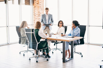 Diverse team of professionals collaborating in a modern office workspace during a productive...