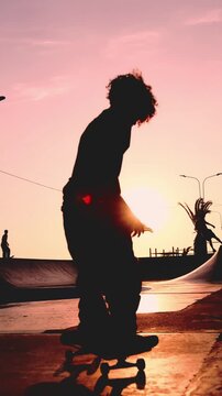 Silhouette of young skateboarder performing tricks at sunset, not recognizable.