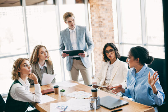 Diverse business team discussing a presentation during a collaborative meeting in a modern office with natural lighting