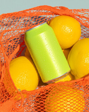 A bright lemonade can lying among lemons on a hot summer day. Fresh chilled drinks.