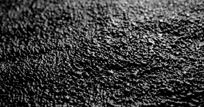 Dark Granular Surface in Motion. Video showing smooth linear movement across a textured black surface with rough granular details, perfect for design and background use.