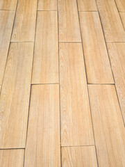 Background of a textured wood-patterned floor. Rough surface of SPC (Stone Plastic Composite) vinyl floor tiles with wood grain pattern. Material is made from natural stone powder combined with resin.