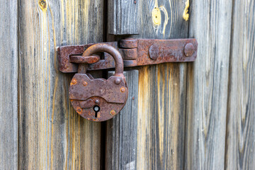 Rusty old padlock on wooden door, vintage security and rustic architectural detail.