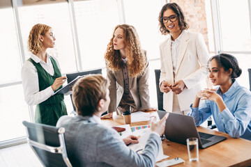 Professional team collaborating in office setting with diverse coworkers discussing work strategies...
