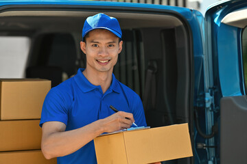 Portrait of a deliveryman in a blue uniform smiles while managing package delivery in the back of a van
