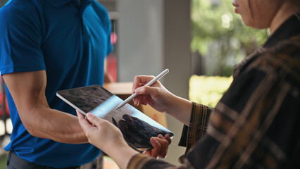 Close-up of a customer using a stylus to sign a delivery confirmation on a tablet, E-signature...