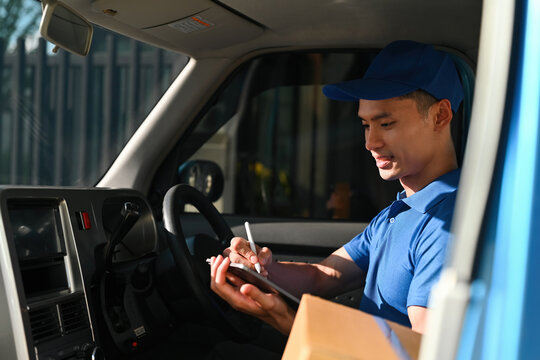 A Delivery man in uniform sits in the driver’s seat, updating shipment records on a tablet - Powered by Adobe
