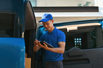 A Logistics worker using stylus and tablet for efficient digital tracking in a delivery vehicle