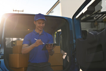 A Professional delivery worker updates parcel info on a tablet, surrounded by boxes in the van, as golden sun flares brighten the scene