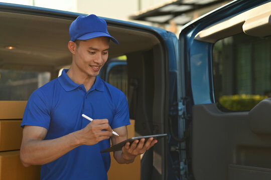 A courier uses a tablet to check delivery orders at the back of a van - Powered by Adobe