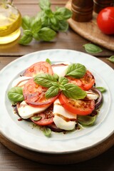 Tasty salad Caprese with mozzarella, tomatoes, basil and spices on wooden table, closeup