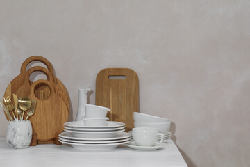 Clean dishware and cutting boards on table near light wall. Space for text