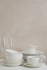 Different clean white dishware and glasses on counter in kitchen, space for text