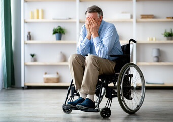 Sad and lonely older impaired man in wheelchair crying at retirement home. Senior disabled male...