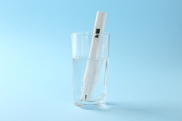 Nitrate tester in glass of water on light blue background