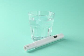 Nitrate tester and glass of water on turquoise background, closeup