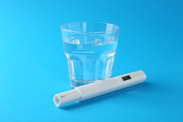 Nitrate tester and glass of water on light blue background, closeup