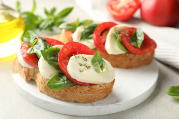 Delicious sandwiches with mozzarella cheese, tomatoes and basil on light grey table, closeup