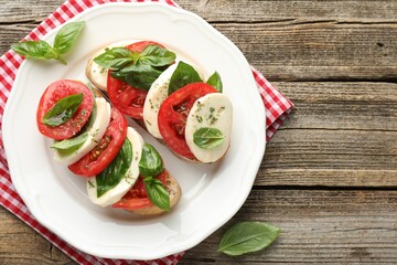 Delicious sandwiches with mozzarella cheese, tomatoes and basil on wooden table, top view. Space for text