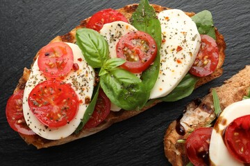 Delicious sandwiches with mozzarella cheese, tomatoes and basil on black table, flat lay