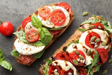 Delicious sandwiches with mozzarella cheese and tomatoes on grey table, flat lay
