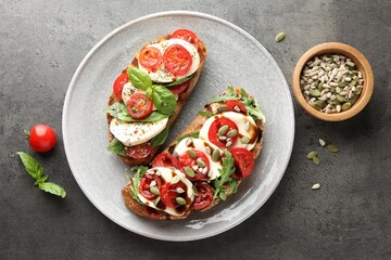Delicious sandwiches with mozzarella cheese and tomatoes on grey table, flat lay