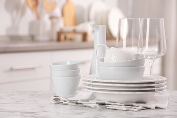 Different clean white dishware and glasses on marble table indoors, space for text