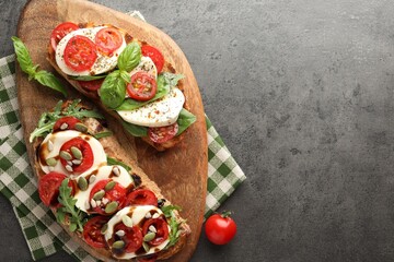 Delicious sandwiches with mozzarella cheese and tomatoes on grey table, top view. Space for text