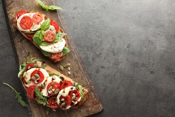 Delicious sandwiches with mozzarella cheese and tomatoes on grey table, top view. Space for text