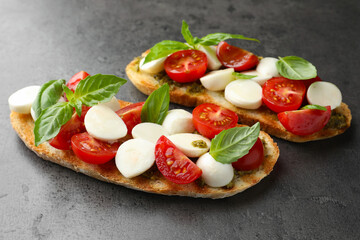 Delicious sandwiches with mozzarella cheese, tomatoes and basil on grey textured table, closeup