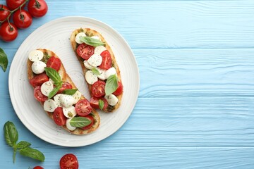 Delicious sandwiches with mozzarella cheese, tomatoes and basil on light blue wooden table, flat lay. Space for text