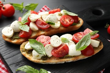 Delicious sandwiches with mozzarella cheese, tomatoes and basil on dark table, closeup