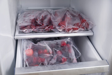 Different frozen berries in plastic bags in open fridge