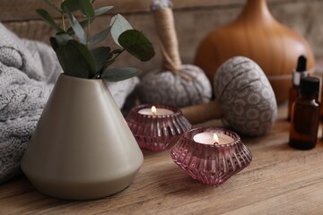 Spa composition with burning candles, vase with eucalyptus branches and herbal bags on wooden...