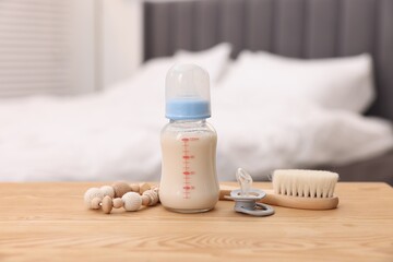 Bottle with milk and baby accessories on table indoors