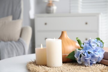 Spa composition with burning candles, aroma oil diffuser and flowers on white table indoors, closeup