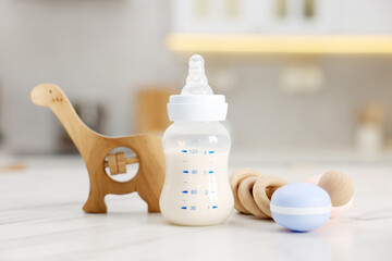 Bottle with milk and baby accessories on table indoors