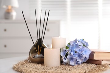 Spa composition of holder with incense sticks, burning candles and flowers on white table indoors, closeup