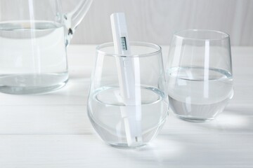Nitrate tester in glass of water on white wooden table, closeup
