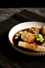 Detail of pempek lenjer and other fishcakes soaking in cuko sauce with cucumber pieces. Authentic...