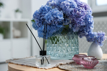 Spa composition with burning candles, reed air freshener and beautiful hydrangea flowers on table